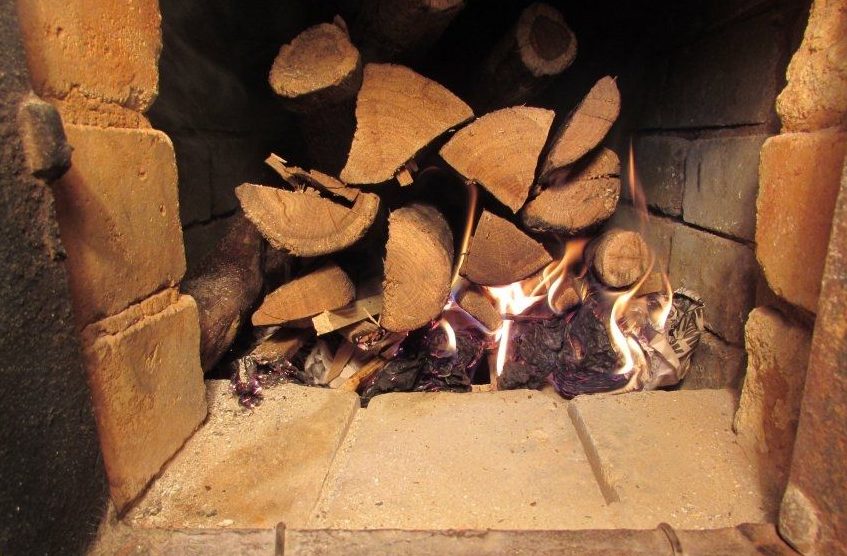 Laying firewood in a stove with a wick.