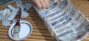 Cover the plastic canister blank twice with newspaper strips on both sides