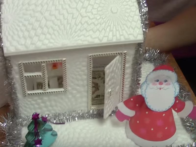 We place a Santa Claus toy near the house.