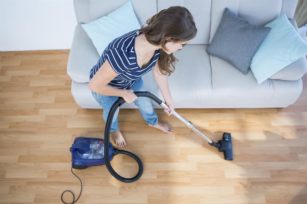 A woman is vacuuming.